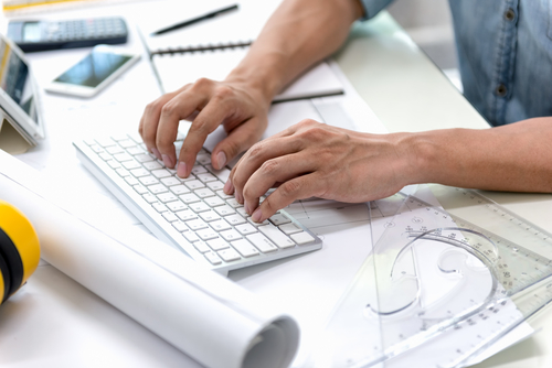 Designer at his desk using a computer keyboard