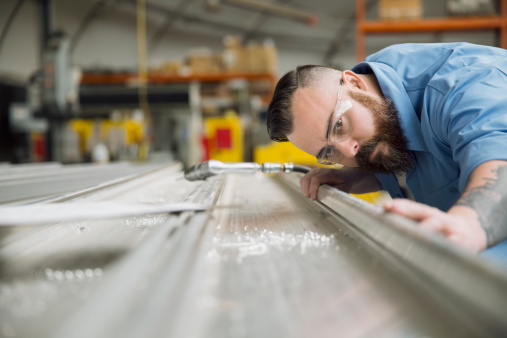 Worker examining sheet metal in manufacturing plant